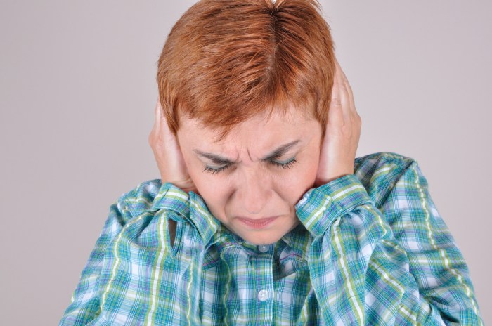 Frowning woman covering her ears with hands